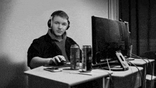 a man wearing headphones sits at a desk in front of an asus computer