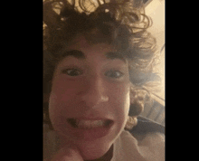 a close up of a young man with curly hair making a funny face