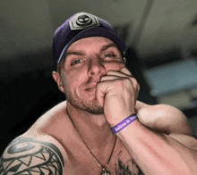 a shirtless man wearing a purple hat and a wristband that says " believe in yourself "