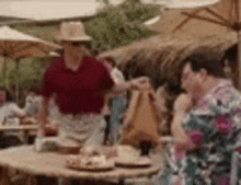 a man in a hat is standing next to a woman sitting at a table at a restaurant .