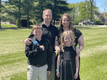 a family posing for a picture in a field with trees in the background