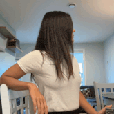 a woman in a white t-shirt is leaning on a white chair
