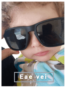 a baby wearing sunglasses with the words " eae vei " below it