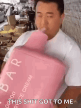 a man is drinking from a large pink bottle of ice cream