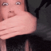 a woman is covering her mouth with her hand and making a surprised face .