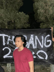 a man in a red shirt holds a black banner that says tabang 2.0