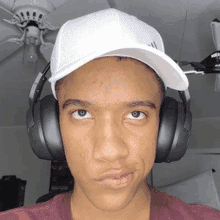 a young man wearing headphones and a hat is making a face .