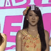 a woman with a flower in her hair is standing in front of a pink sign that says fight