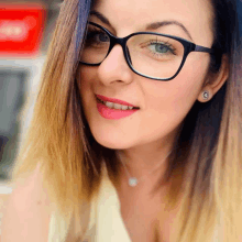 a close up of a woman wearing glasses and a necklace