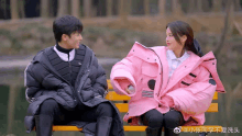 a man and a woman are sitting on a bench with chinese writing behind them