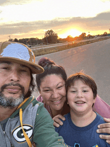 a man wearing a green bay packers sweatshirt poses for a picture with his family