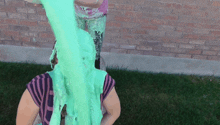 a woman covered in green slime is standing in front of a brick building