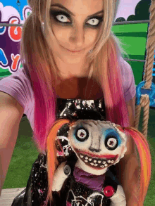 a woman with pink hair is holding a stuffed doll in her hands .