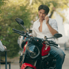 a man is sitting on a red ducati bike