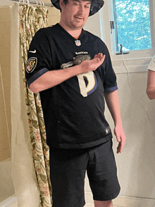 a man in a black ravens jersey holds a cat