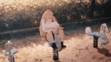 a girl is sitting on a seesaw in a sandy area .