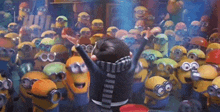 a group of minions are gathered around a person with their arms in the air .