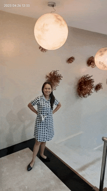 a woman in a plaid dress is standing in front of a wall with a moon hanging from it