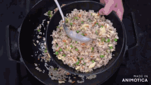 a bowl of rice and vegetables is being stirred with a ladle and the words made in animotica are on the bottom