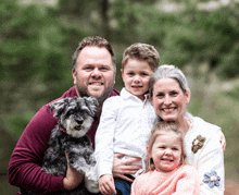 a family posing for a picture with a small dog