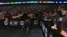 a man in a black vest is dancing in front of a crowd at a wrestling event sponsored by tnt