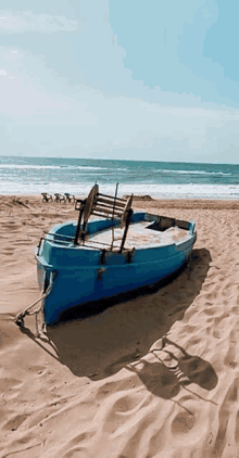 a blue boat is sitting on the sand on a beach .