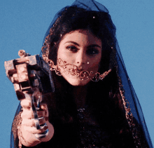 a woman wearing a veil and nose ring holds a gun