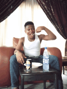 a man sitting on a couch with a can of pepsi and a bottle of water