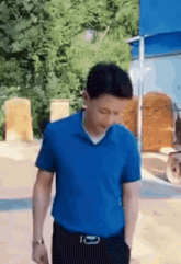 the man is wearing a blue shirt and black pants .
