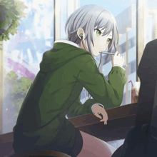 a girl wearing headphones and a green jacket sits at a table