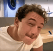 a man with curly hair is making a funny face with his eyes closed and his mouth open .
