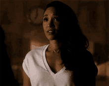 a woman in a white t-shirt is standing in a dark room with her eyes closed .