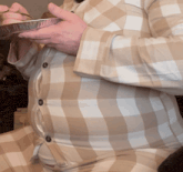 a man wearing a plaid shirt is holding a tin foil container