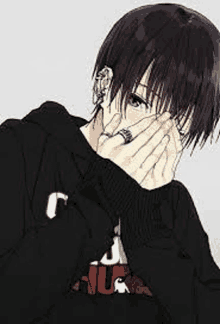 a boy in a black hoodie is covering his face with his hand .