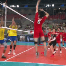 a man in a red shirt with the number 5 on it is jumping in the air while playing volleyball