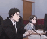 a man and a woman are sitting at a desk in front of a microphone .