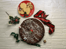 a christmas cake sits next to a plate of cookies and a ribbon that says christmas happy new year