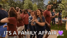 a group of people are dancing in a park with the words `` it 's a family affair '' written on the screen .