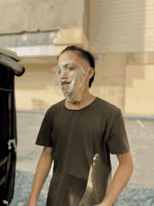 a man wearing a plastic mask on his face stands in front of a building