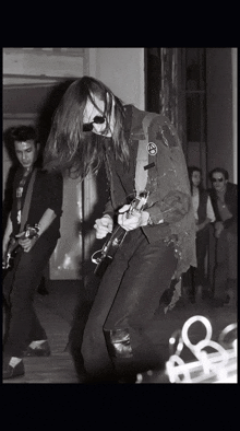 a black and white photo of a man playing a guitar with a patch on his jacket that says ' a ' on it