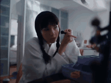 a woman is applying makeup to her face with a brush while sitting at a table .