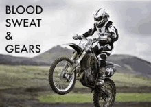 a man is riding a dirt bike on a dirt road in a field .