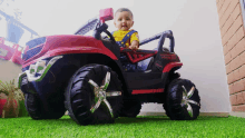 a baby is sitting in a red and black jeep with the word vibe on the front