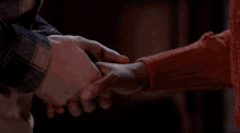 a man and a woman holding hands in a dark room