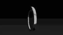 a silver ring is spinning on a black background