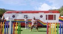 a man in a rainbow outfit stands in front of a trailer with a sign that says i love you to the sky