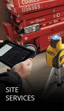 a person holding a tablet in front of a skyjack lift