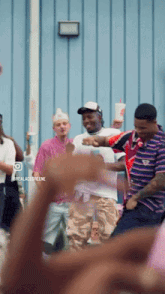 a group of people are dancing in front of a blue wall with the words realacidgreene on the bottom