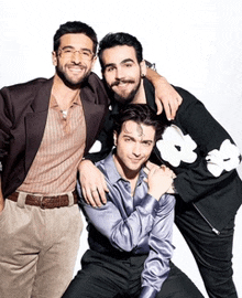 three men are posing for a picture and one of them is wearing a jacket with flowers on it