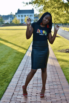 a woman wearing a t-shirt that says living my realtor life stands on a sidewalk